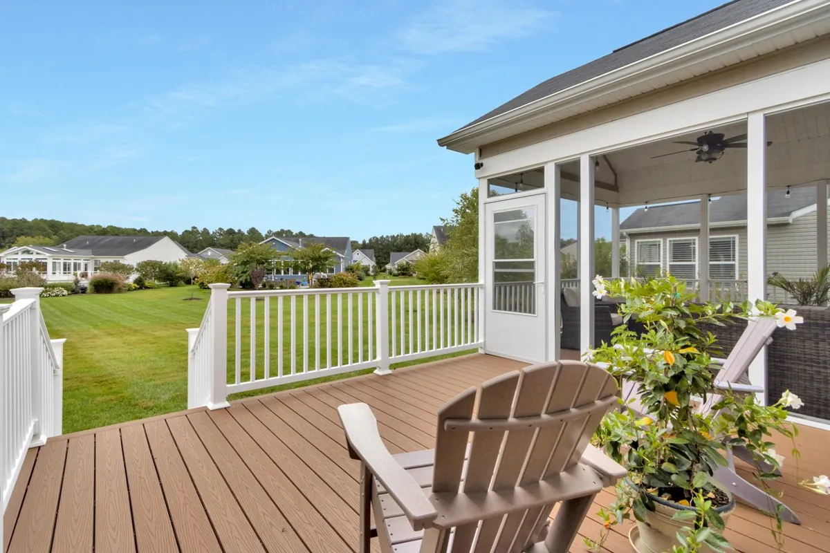 Brown composite deck with white railing and an Adirondack chair beside a screened porch