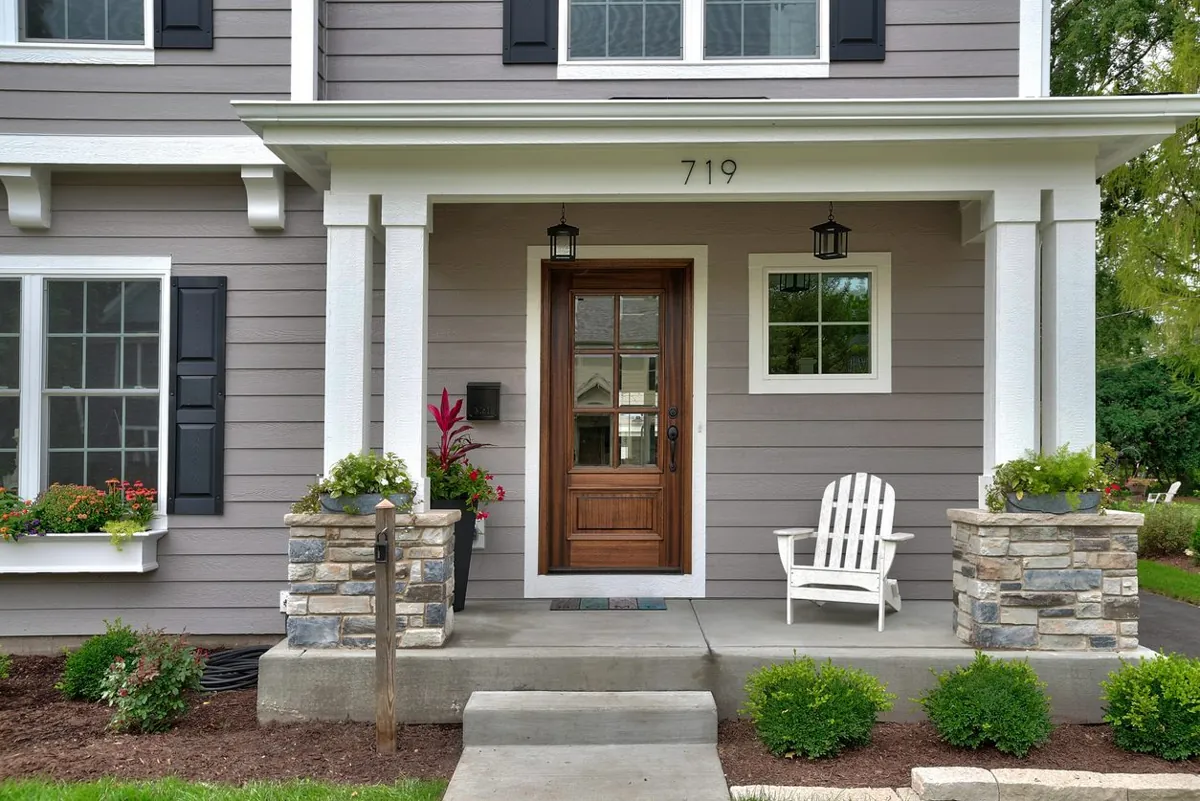 Warm gray craftsman porch with stone column bases and a wood front door