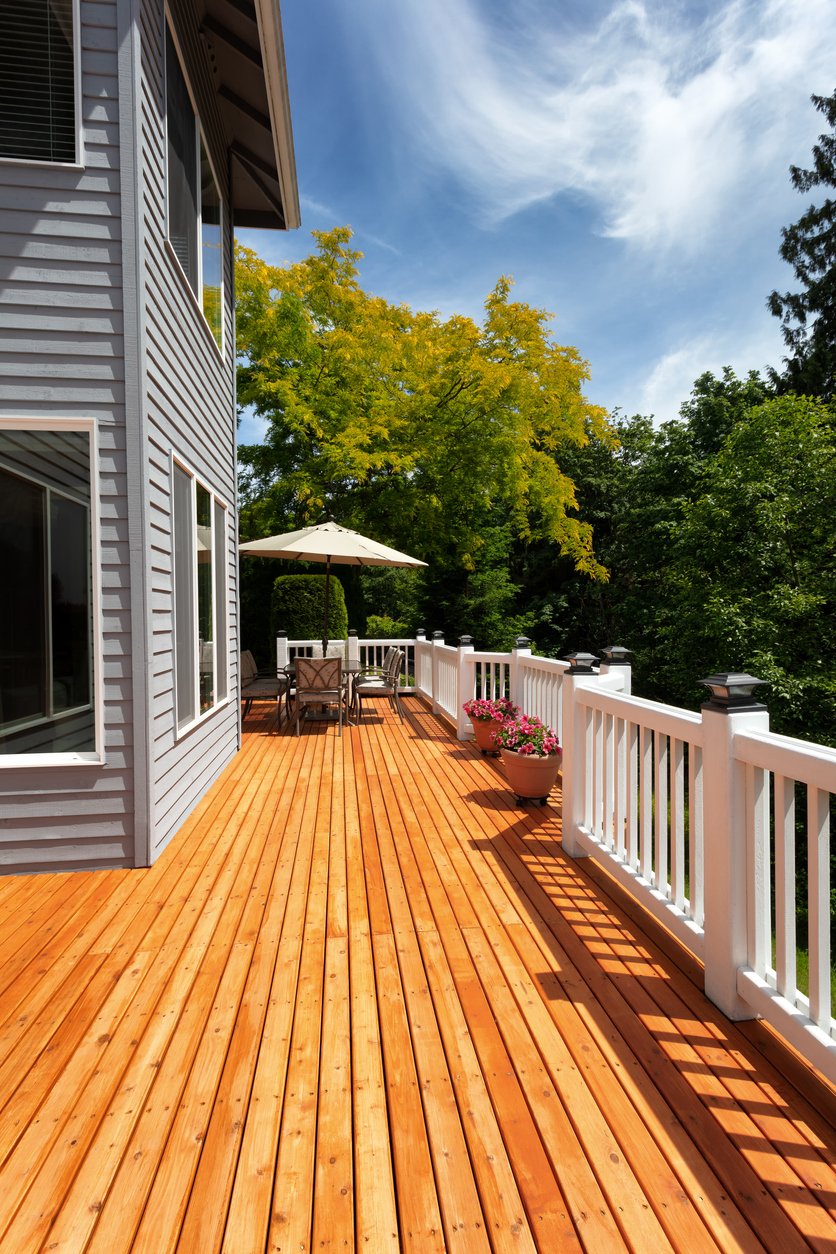 Cedar deck with white railing, a patio umbrella, and outdoor dining furniture