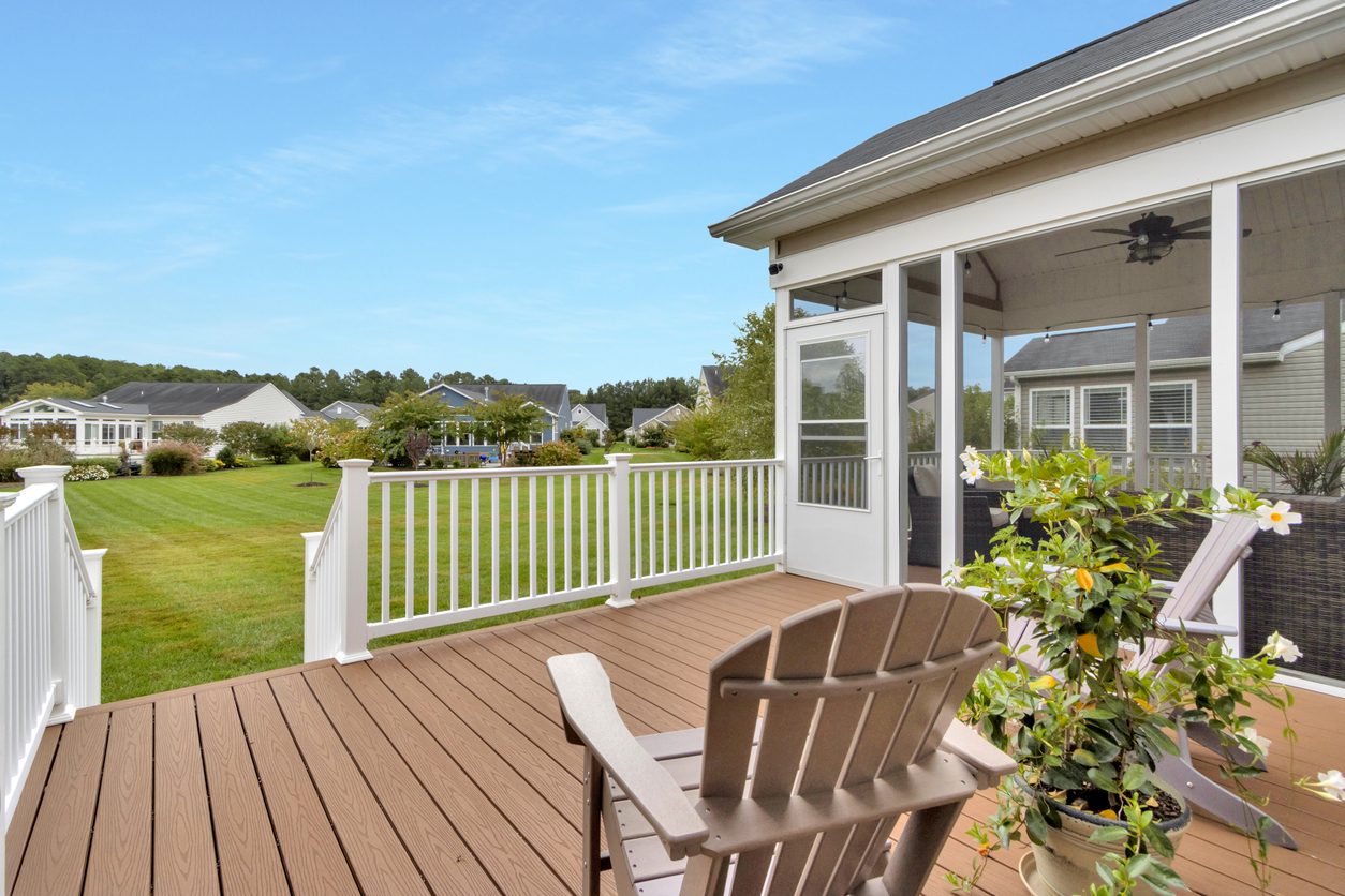 Brown composite deck with white railing and an Adirondack chair beside a screened porch