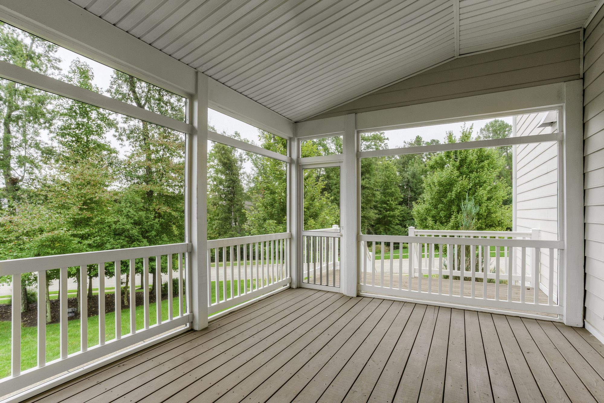 Screened-in porch with gray composite decking and a white railing