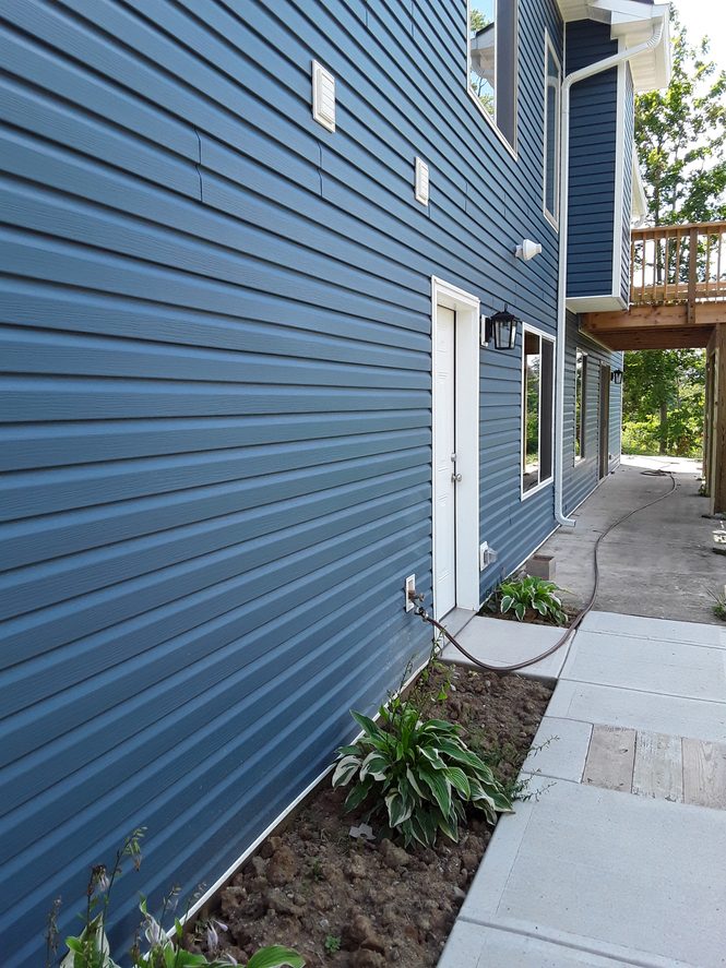 Blue lap siding along a home's side wall with a white entry door and walkway