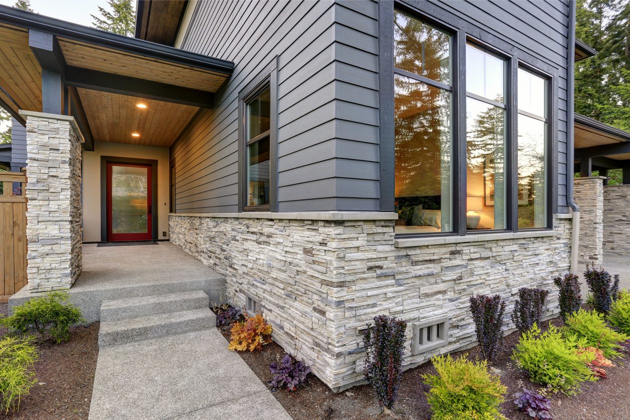 Dark gray lap siding on a modern home with a stacked stone base