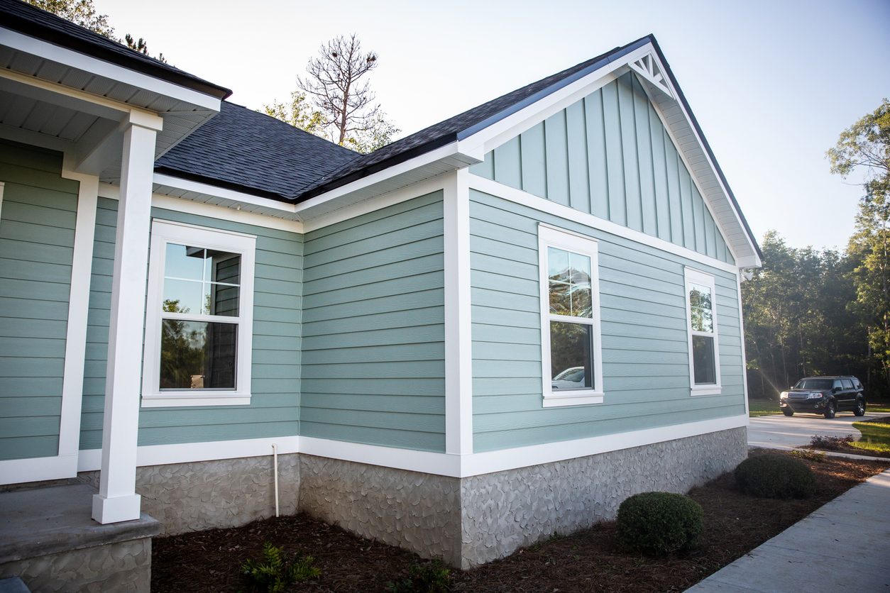 Sage green home with lap and board-and-batten siding over a stone foundation