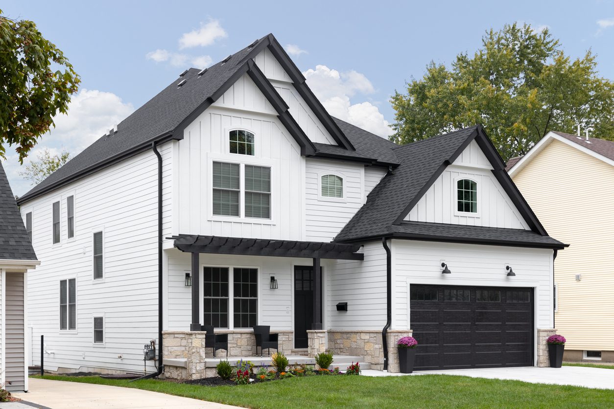 White modern farmhouse with mixed lap and board-and-batten siding and black trim