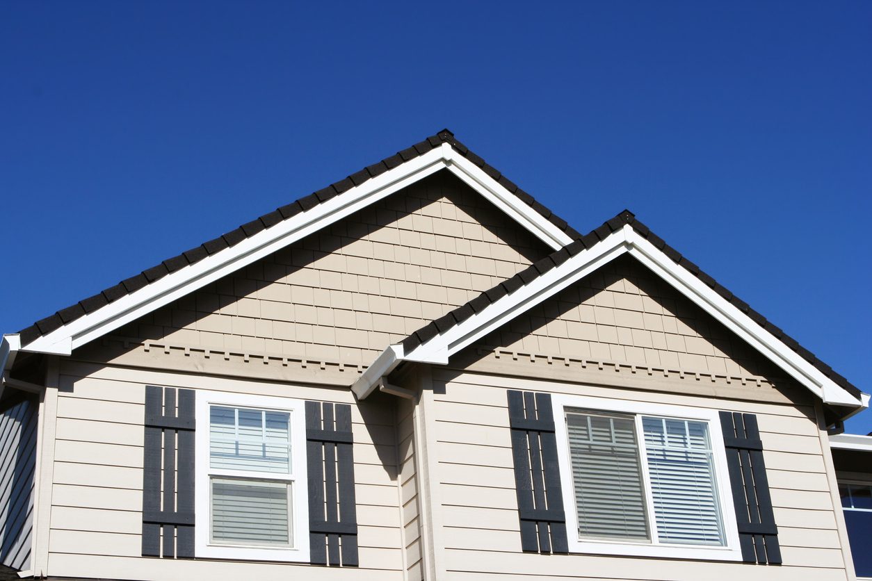 Pair of white-trimmed windows with black shutters on tan gables