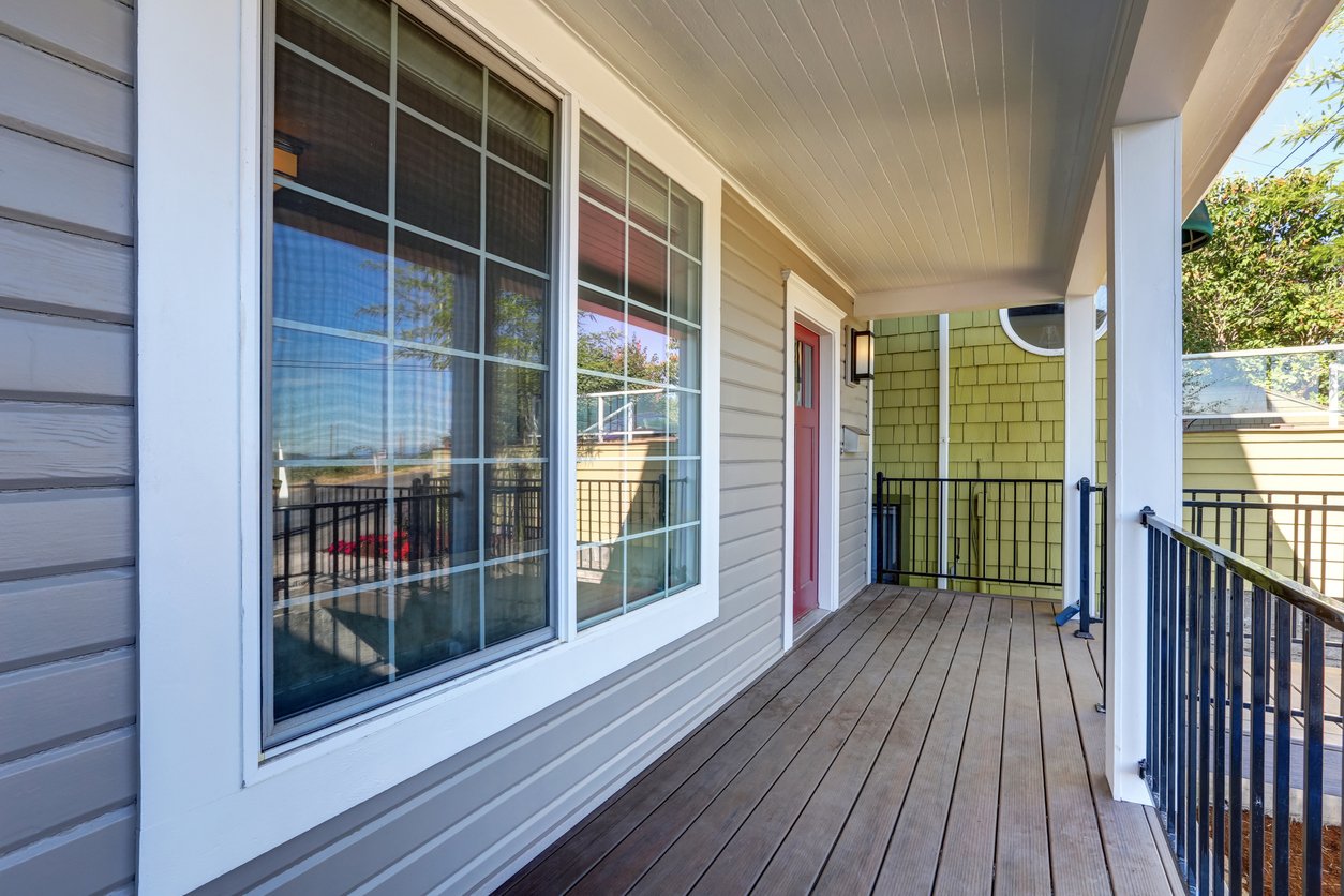 Covered porch with white colonial-grid slider windows on a gray-sided home