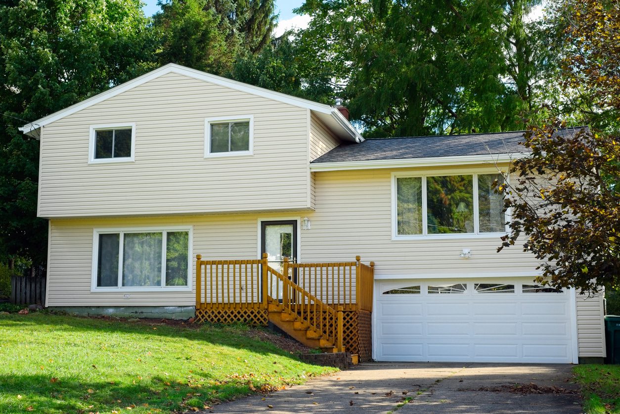Tan split-level home with fresh lap siding, white trim, and new windows